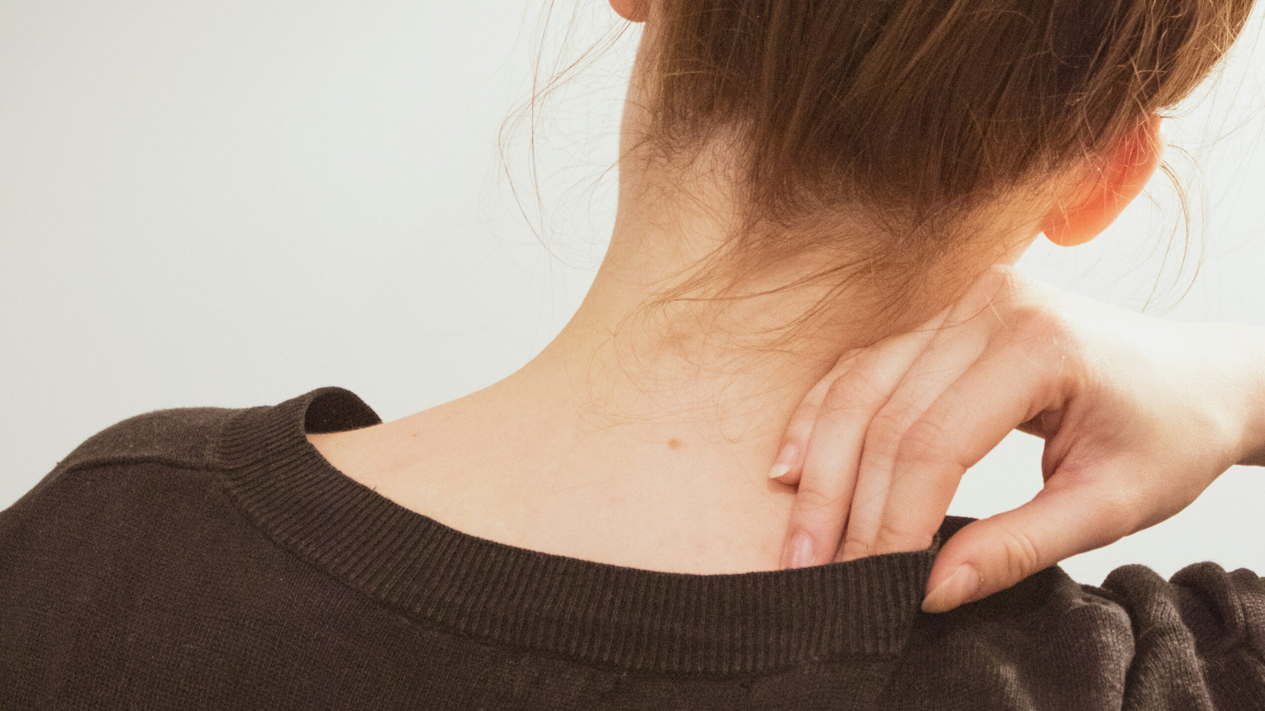 Femme massant sa nuque tendue, un signe de stress possible