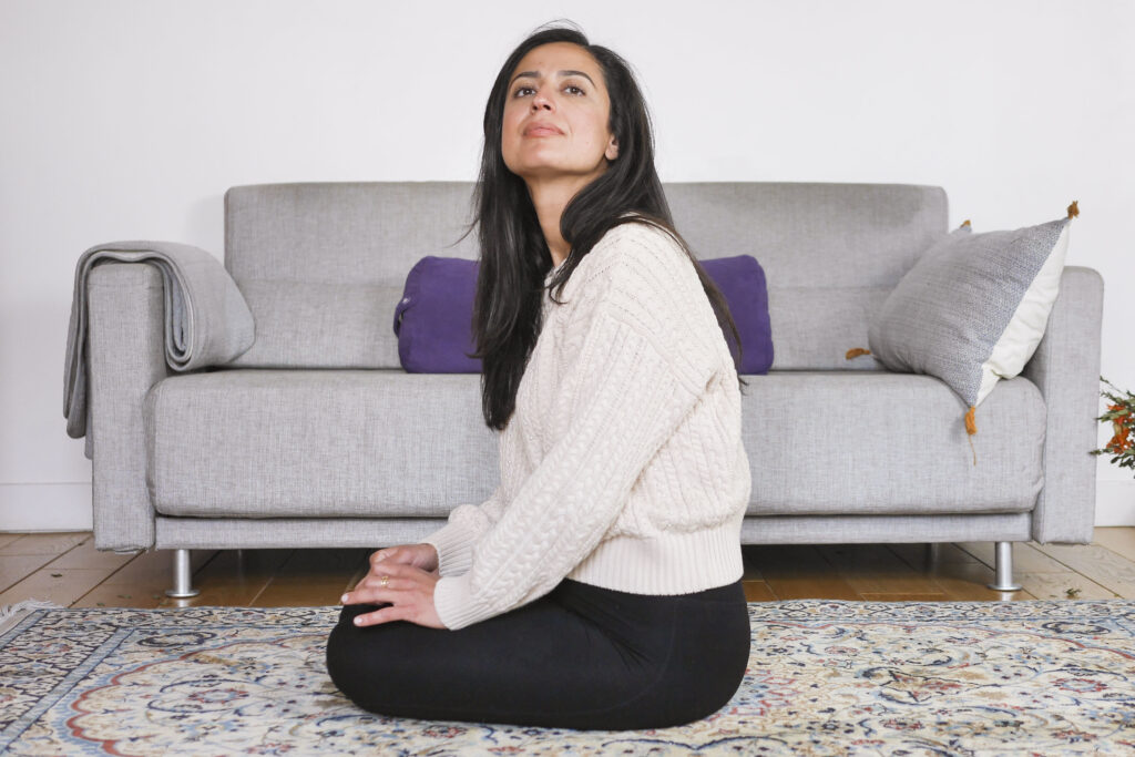 Femme assise chez elle, attentive à son environnement, évoquant une difficulté à se relâcher
