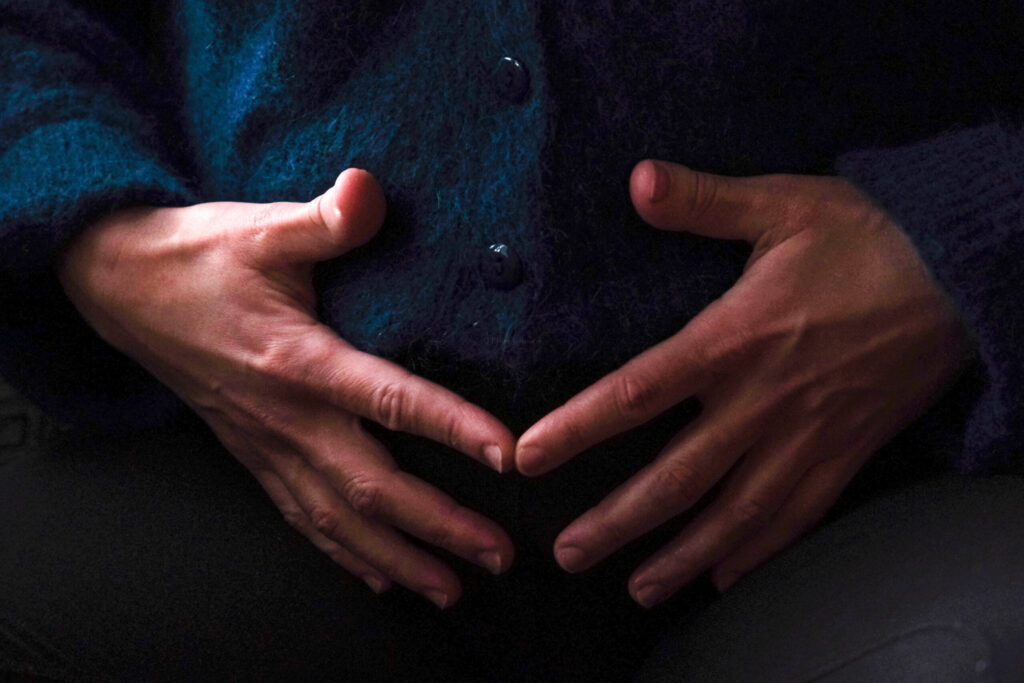 Geste d'autocontact, main posée sur le bas-ventre, évoquant la thématique de la fertilité
