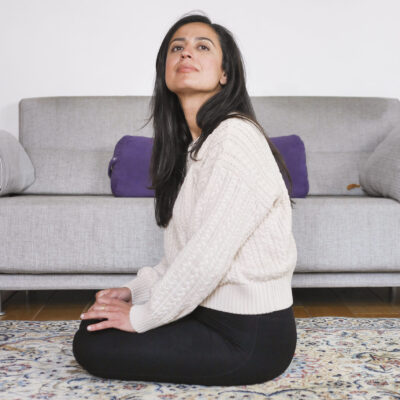 Femme assise chez elle, attentive à son environnement, évoquant une difficulté à se relâcher